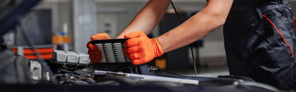 Mechanic replacing a car engine air filter in a service bay