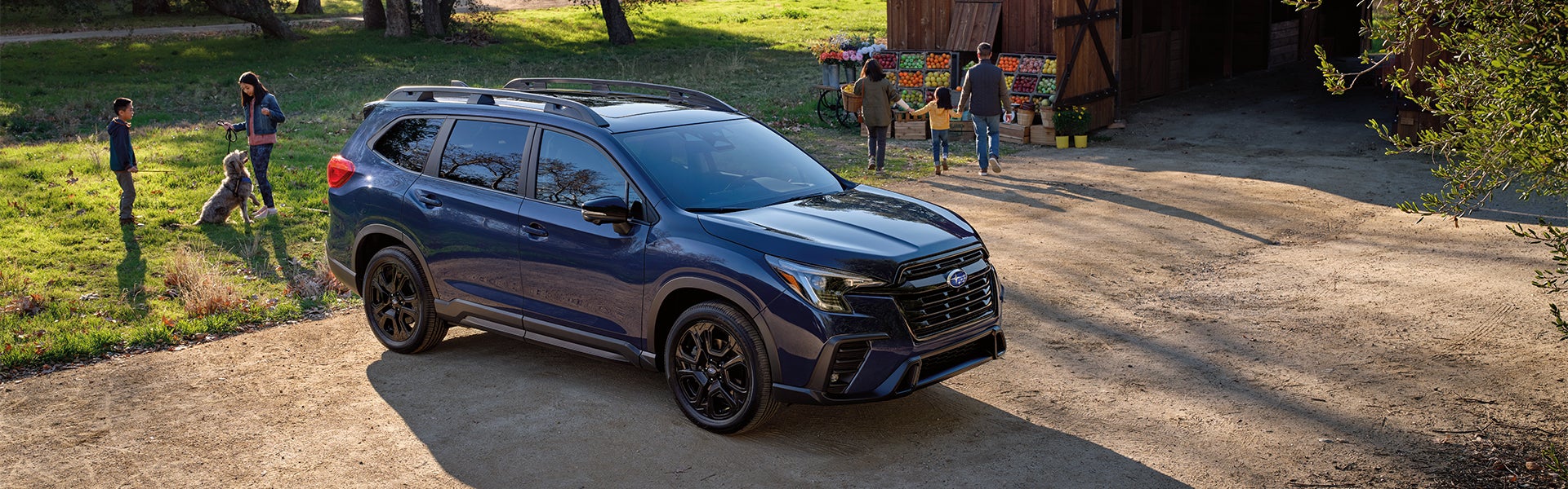 Dark blue Subaru SUV parked outdoors on a dirt path with a family nearby