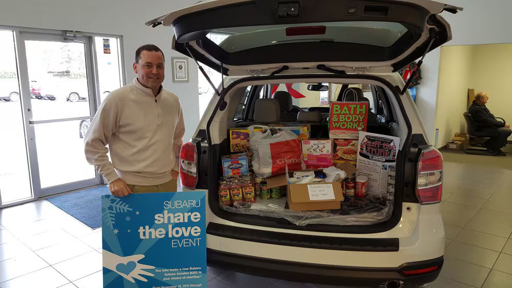 share the love event man with donations Grand Forks Subaru in Grand Forks ND